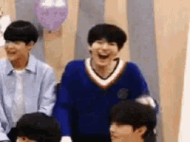 a group of young men are sitting in a room with balloons and laughing .