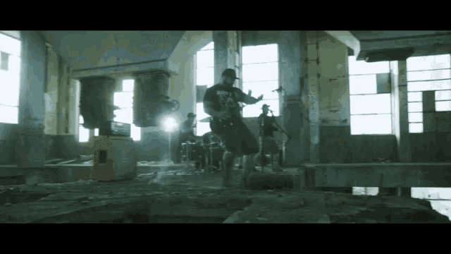 a man playing a guitar in a room with a few other people