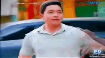 a man in a white shirt is standing in front of a car on a tv screen