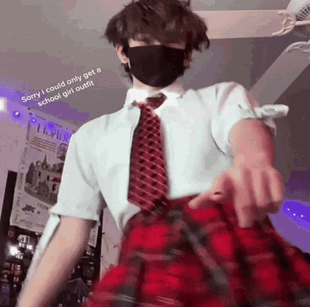 a young man wearing a mask and a plaid skirt is standing in a room .