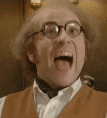 a man wearing glasses and a vest is making a funny face with his tongue out .