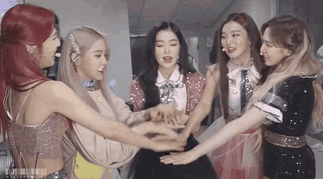 a group of girls are standing in a circle with their hands on each other .