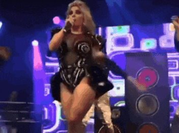a woman is singing into a microphone while dancing on stage
