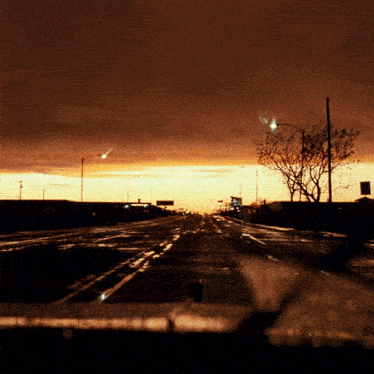 a road with a sunset in the background and a sign that says ' a ' on it