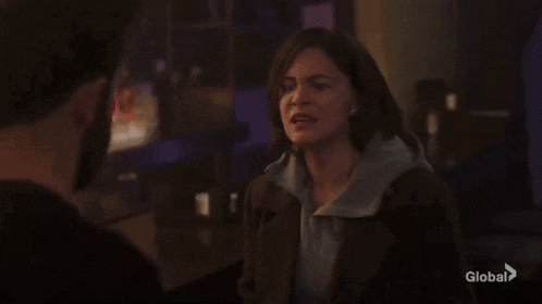 a woman is standing next to a man in a dark room and making a funny face .