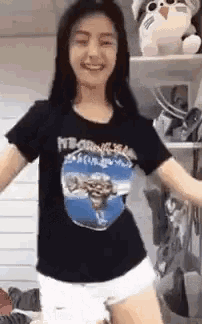 a young woman wearing a black t-shirt and white shorts is dancing in a room .