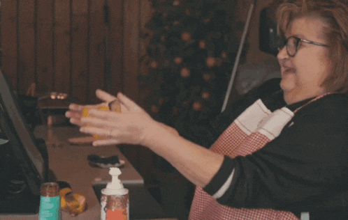 a woman wearing glasses and an apron is holding a yellow object in her hands
