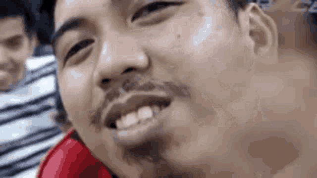 a close up of a man 's face with a beard smiling and looking at the camera .