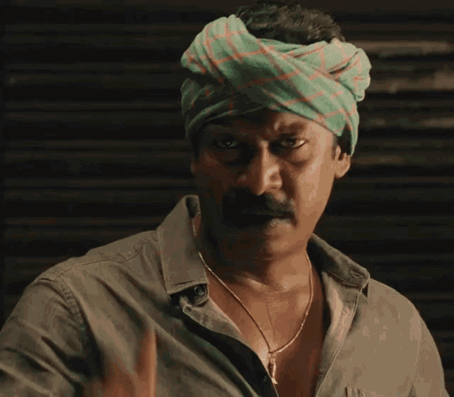 a man wearing a turban and a necklace looks angry