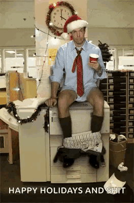 a man wearing a santa hat and tie is sitting on a copier with his pants down .