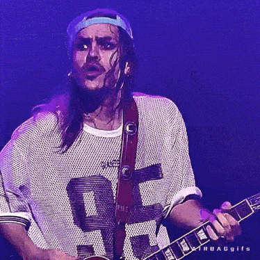 a man with long hair and a beard is playing a guitar and wearing a jersey with the number 22 on it