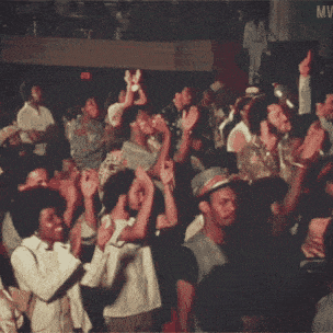 a crowd of people with their hands in the air and the word mw on the bottom right