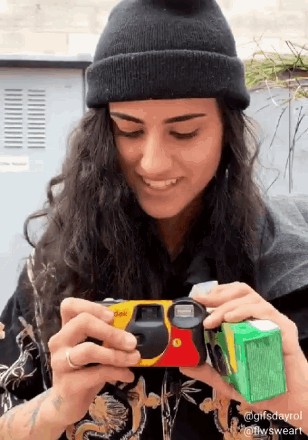 a woman is holding a kodak camera in her hands