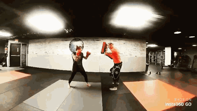 two women are boxing in a gym with insta360 go in the corner
