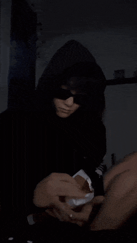 a person wearing a black hoodie is holding a piece of paper that says ' snickers ' on it