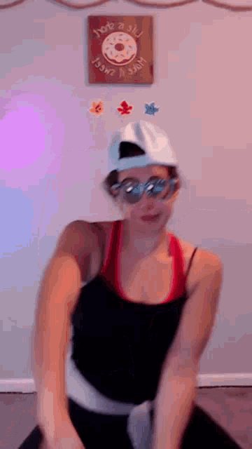 a woman wearing sunglasses and a baseball cap is dancing