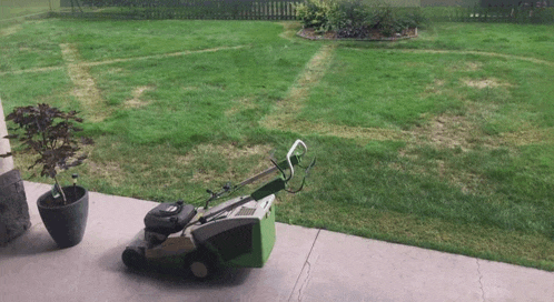 a green lawn mower is sitting on a concrete porch