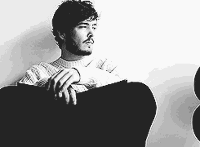 a man with a beard is sitting in a chair .