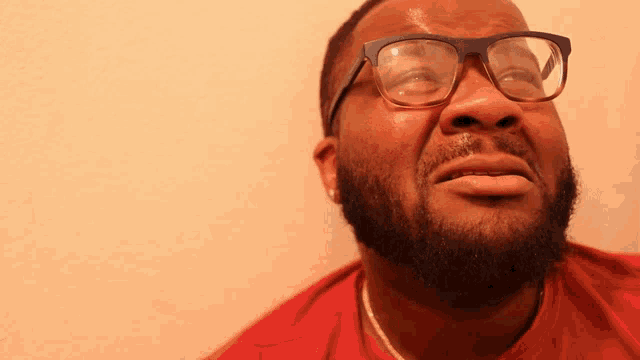 a man wearing glasses and a red shirt looks up at something