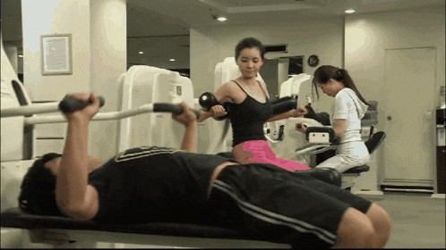 a man is lifting a barbell while a woman watches
