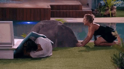 a woman in a black dress is kneeling next to a man in a towel .