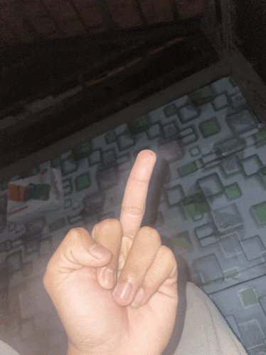 a person 's hand is giving the middle finger in front of a tiled floor
