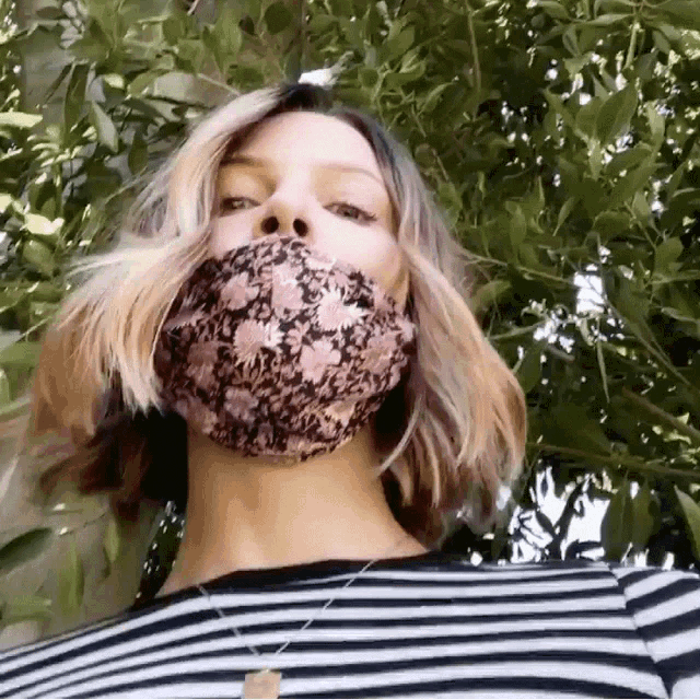 a woman wearing a striped shirt and a floral face mask
