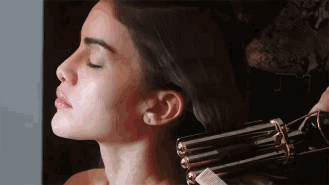 a woman with her eyes closed is being curled with a hair curler