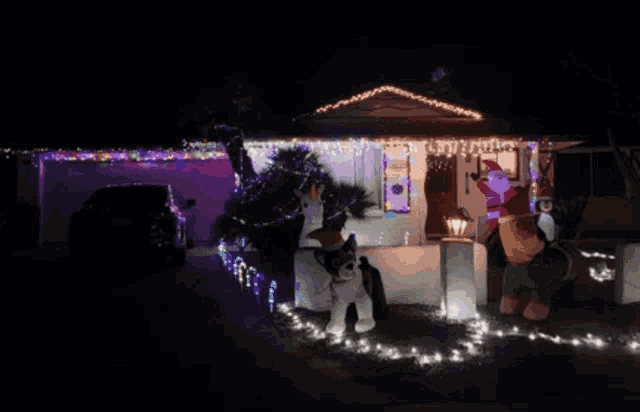 a house is decorated with christmas lights and a santa claus statue