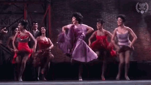 a group of women are dancing on a stage in a theatre .
