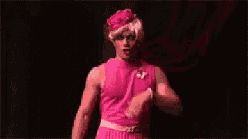 a man in a pink dress is blowing a kiss .