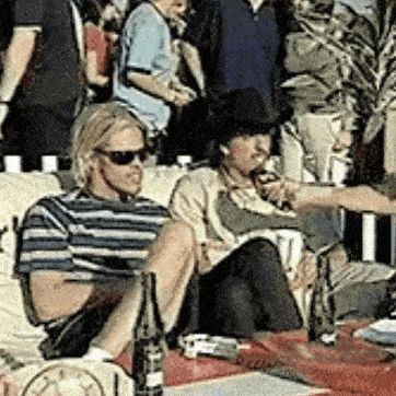 a man wearing sunglasses is sitting on a couch with a bottle of beer