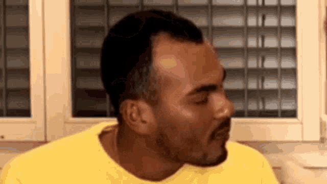 a man with a beard and a yellow shirt is making a funny face .