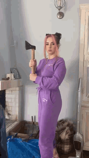 a woman in a purple jumpsuit holds a large axe