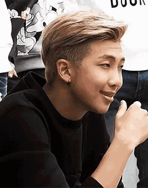 a young man wearing a black hoodie and earrings is smiling while sitting down .