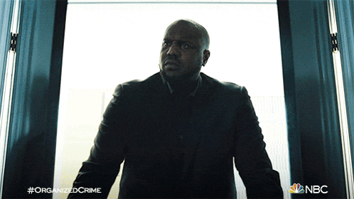 a man in a suit is standing in front of a window with the hashtag organized crime