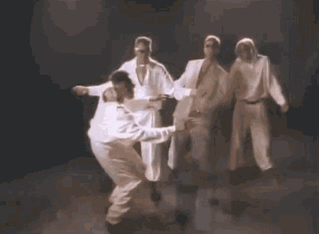 a group of men are dancing together on a stage .