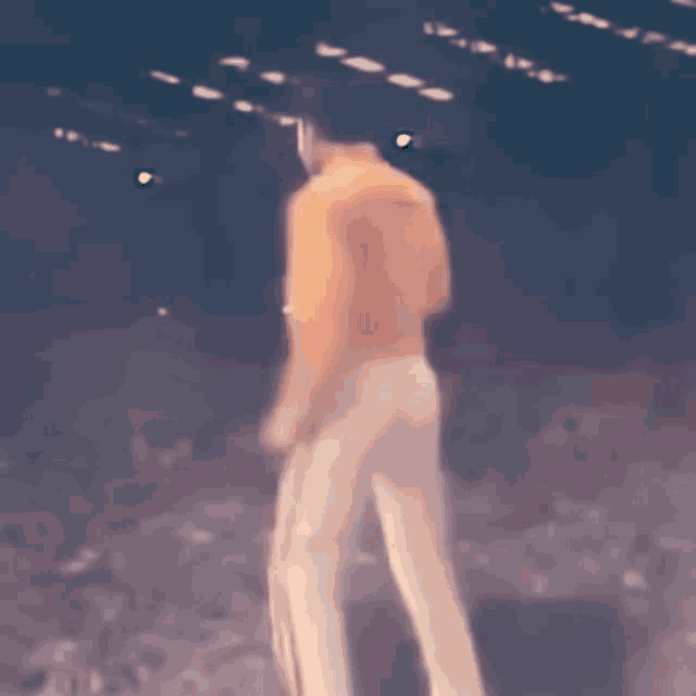 a blurry picture of a man in a yellow jacket and white pants dancing on a stage .