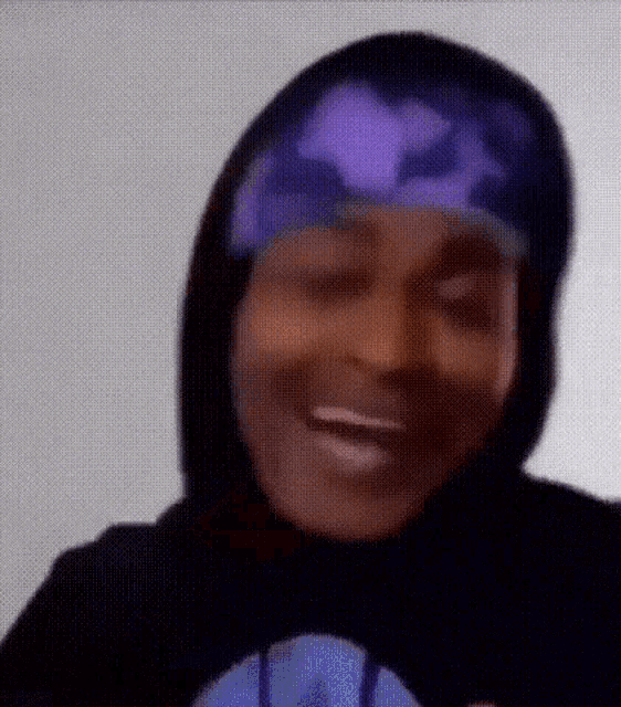 a close up of a person wearing a purple hat and a black hoodie .