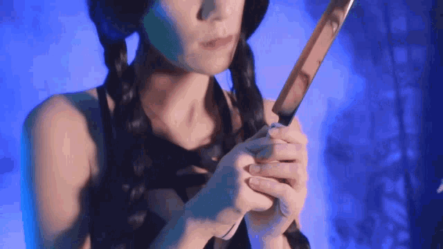 a woman is holding a knife in her hands with a blue background