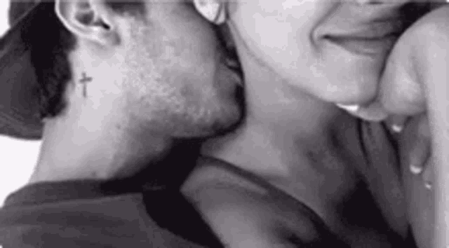 a man and a woman are kissing with a cross tattoo on the back of his neck .