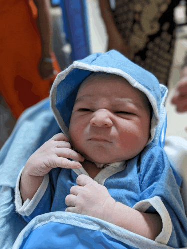 a newborn baby wearing a blue robe and hood