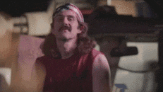 a man with a bandana on his head is standing in a room with a smoke coming out of his mouth .
