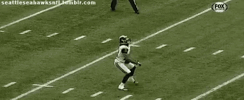 a football player is running with the ball on a field while a referee watches .