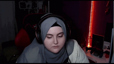 a woman wearing a hijab and headphones is sitting in a gaming chair that says xdrive