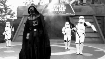 a black and white photo of darth vader and stormtroopers dancing in front of a sign that says star wars legends .