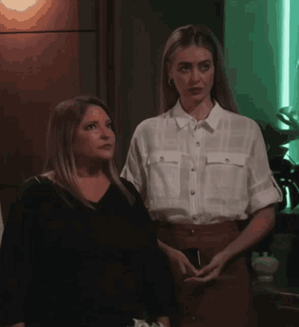 two women are standing next to each other in a room