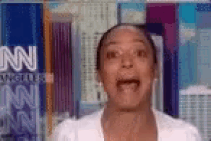 a woman in a white shirt is making a funny face in front of a cnn logo .