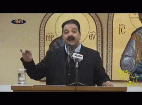 a man stands at a podium giving a speech in front of a wall with icons and the letter mp on it
