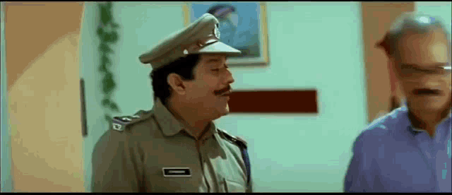 a police officer is standing next to another man in a room .